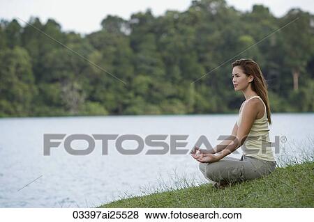 Stock Photo - Woman meditating by lake. Fotosearch
