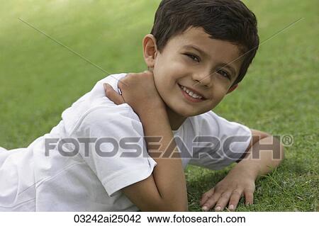 young boy resting on grass, smiling View Large Photo Image Stock Image - young boy resting on grass, smiling. Fotosearch