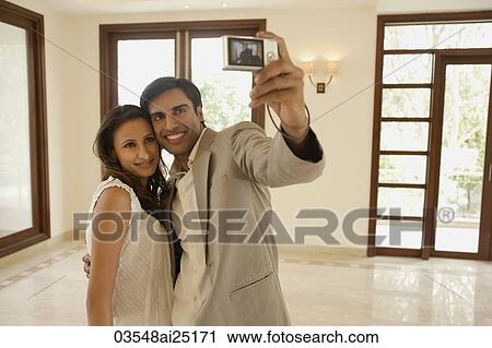 Stock Image - Young couple taking picture in empty home. Fotosearch