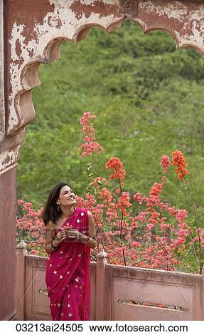 Stock Photography - young woman in sari holding flowers. Fotosearch