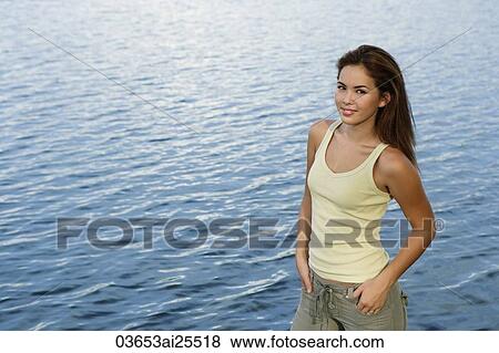 Stock Photo - Young woman standing by a lake. Fotosearch
