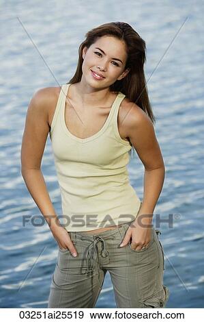 Stock Photo - Young woman standing in front of a lake. Fotosearch