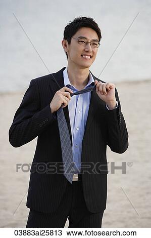 Businessman on beach, removing tie View Large Photo Image Stock Image - Businessman on beach, removing tie. Fotosearch