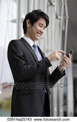 Stock Image - Businessman sending message on mobile device. Fotosearch