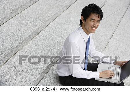 Businessman sitting on steps ans working on laptop View Large Photo Image Stock Photo - Businessman sitting on steps ans working on laptop. Fotosearch