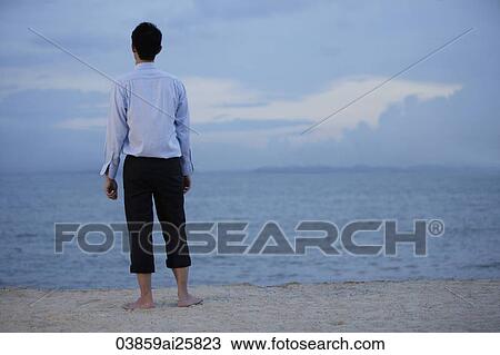 Businessman standing on beach in evening looking at ships View Large Photo Image Stock Image - Businessman standing on beach in evening looking at ships. Fotosearch