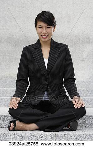 Stock Photography - Businesswoman sitting crossed-legged outside. Fotosearch