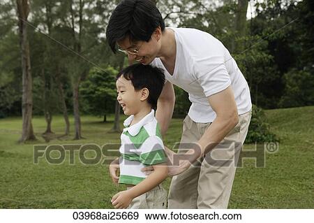 Stock Photo - Father and son playing in park. Fotosearch