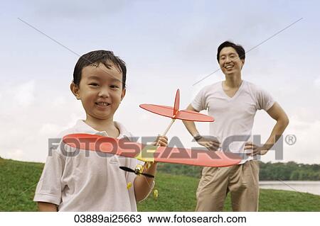 Father watching son holding toy airplane View Large Photo Image Stock Image - Father watching son holding toy airplane. Fotosearch