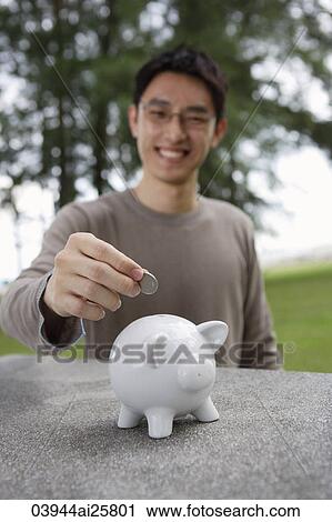 Man putting coin into piggy bank View Large Photo Image Stock Image - Man putting coin into piggy bank. Fotosearch