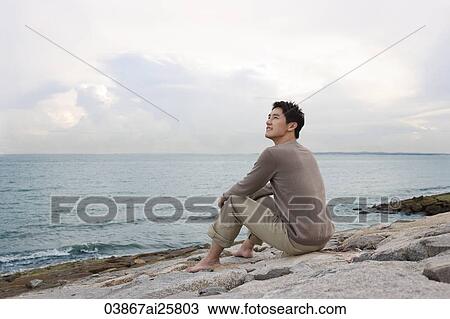 Man sitting by shore looking out to sea View Large Photo Image Stock Image - Man sitting by shore looking out to sea. Fotosearch