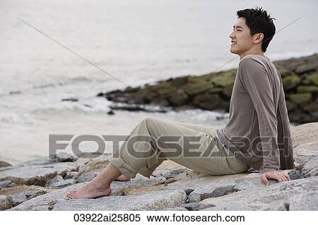Man sitting on sea shore View Large Photo Image Stock Photography - Man sitting on sea shore. Fotosearch