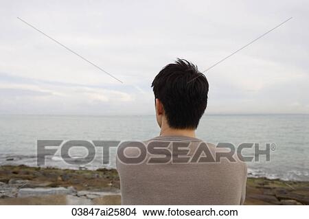 Man sitting seaside looking out to ocean View Large Photo Image Picture - Man sitting seaside looking out to ocean. Fotosearch