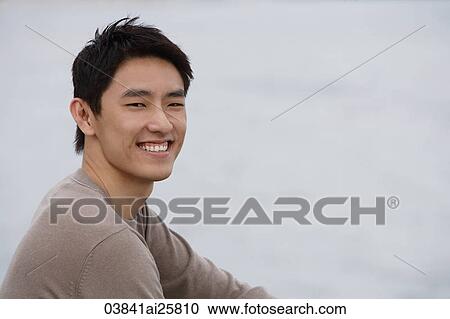 Stock Image - Portrait of man sitting next to water. Fotosearch