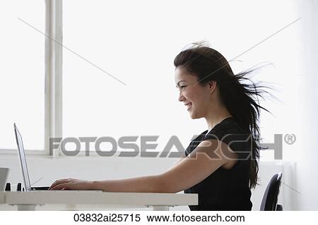 Stock Photography - Profile of young woman at computer. Fotosearch