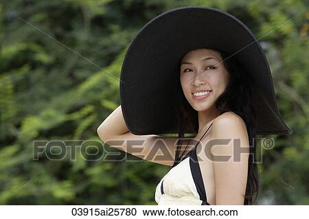Stock Image - Young woman wearing big black hat. Fotosearch