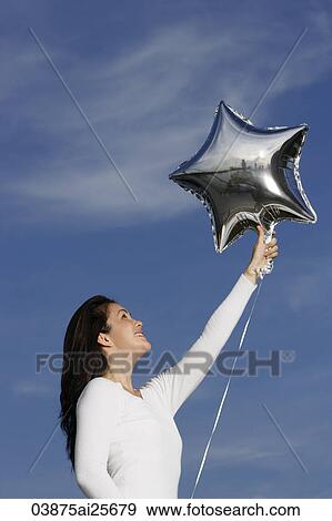 Stock Photo - Young woman with silver star-shaped balloon. Fotosearch