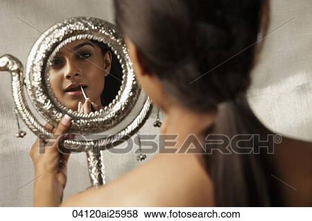 Stock Photo - back view of woman holding up mirror with reflection. Fotosearch