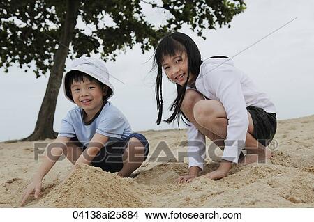 Picture - boy and girl playing in sand near ocean. Fotosearch