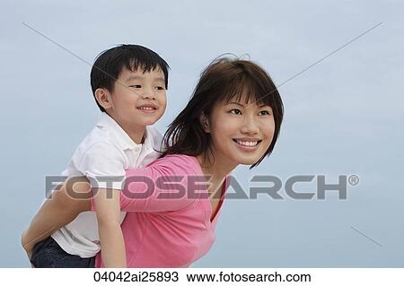 Stock Image - boy riding piggy-back on young woman. Fotosearch