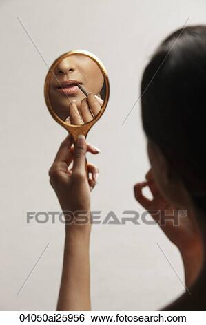 Stock Photograph - hand of woman holding up mirror with reflection. Fotosearch