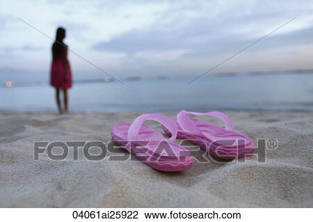 Sandals on sandy beach, woman in background View Large Photo Image Stock Image - Sandals on sandy beach, woman in background. Fotosearch