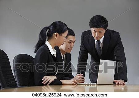 Picture - Three colleagues working at laptop in conference room. Fotosearch