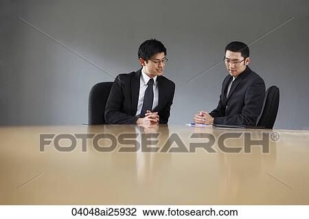 Stock Image - Two colleagues meeting in a conference room. Fotosearch