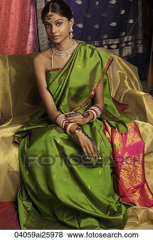 Stock Photo - woman wearing sari, surrounded by sari fabric, decorated with henna tattoos, jewelry and bindi. Fotosearch
