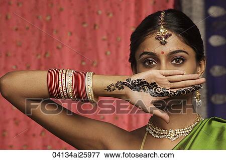 Stock Photo - woman with hands decorated in henna, standing against wall of sari fabric. Fotosearch