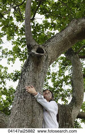 Stock Image - Young girl hugging a tree. Fotosearch