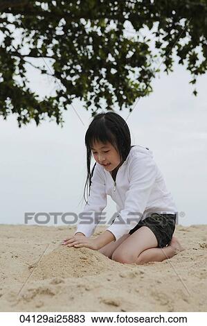 Young girl playing in the sand near ocean View Large Photo Image Stock Image - Young girl playing in the sand near ocean. Fotosearch