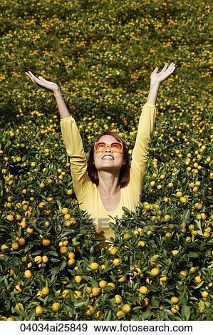 Stock Photo - Young woman among orange plants. Fotosearch