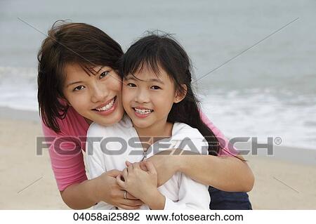 Stock Image - young woman and girl cheek to cheek. Fotosearch