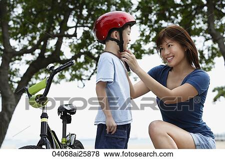 Young woman fastening helmet on boy View Large Photo Image Stock Photo - Young woman fastening helmet on boy. Fotosearch