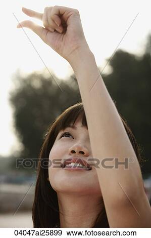 Stock Photo - Young woman holding sunlight with her fingers. Fotosearch