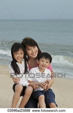 Young woman hugging boy and girl on beach View Large Photo Image Stock Photo - Young woman hugging boy and girl on beach. Fotosearch