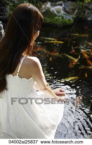Young woman in white dress sitting by pond View Large Photo Image Stock Photo - Young woman in white dress sitting by pond. Fotosearch