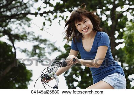 Young woman riding bike View Large Photo Image Stock Image - Young woman riding bike. Fotosearch