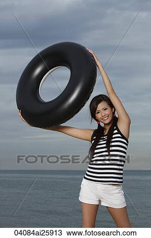 Young woman smiling and holding up inner tube View Large Photo Image Stock Image - Young woman smiling and holding up inner tube. Fotosearch