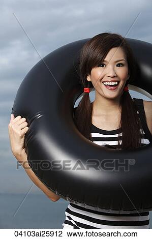 Young woman smiling through middle of inner tube View Large Photo Image Stock Image - Young woman smiling through middle of inner tube. Fotosearch