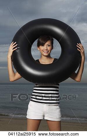 Stock Photography - Young woman smiling through middle of inner tube. Fotosearch