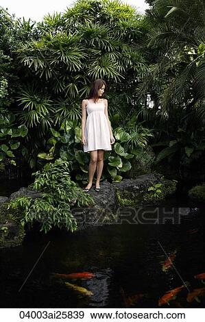 Young woman standing above koi pond View Large Photo Image Stock Photo - Young woman standing above koi pond. Fotosearch