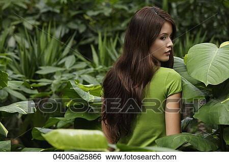Young woman standing among plants View Large Photo Image Stock Photograph - Young woman standing among plants. Fotosearch