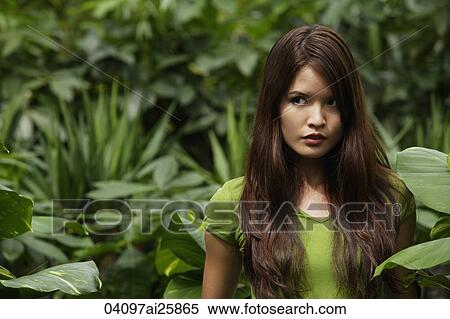 Young woman standing among plants View Large Photo Image Stock Photography - Young woman standing among plants. Fotosearch