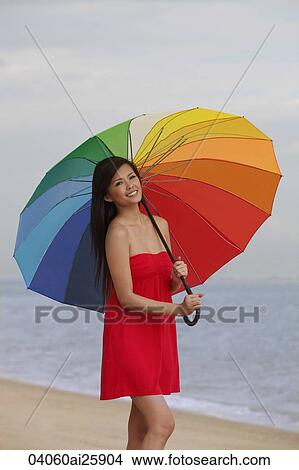 Picture - Young woman standing under bright umbrella. Fotosearch