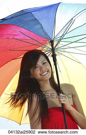 Young woman standing underneath umbrella View Large Photo Image Stock Image - Young woman standing underneath umbrella. Fotosearch