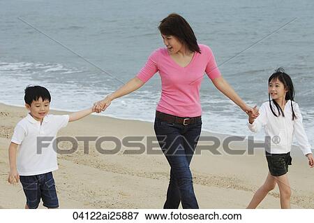 Stock Photo - Young woman walking on beach with boy and girl. Fotosearch