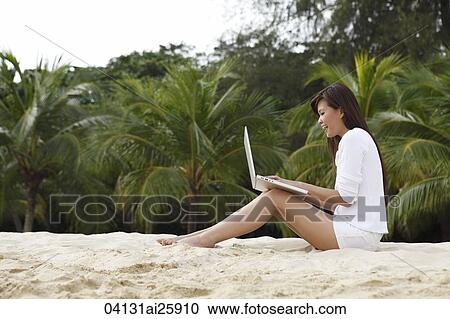Young woman working on laptop on beach View Large Photo Image Stock Image - Young woman working on laptop on beach. Fotosearch