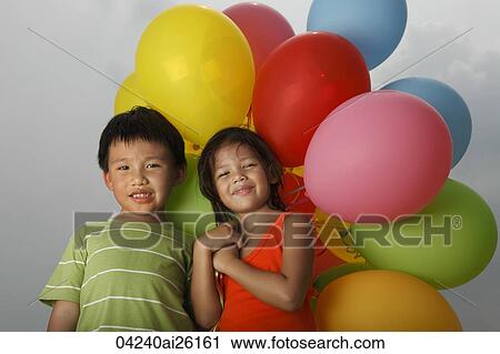 Stock Image - Boy and girl holding balloons.. Fotosearch